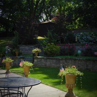 A serene garden with a patio and decorative planters under the shade of trees.