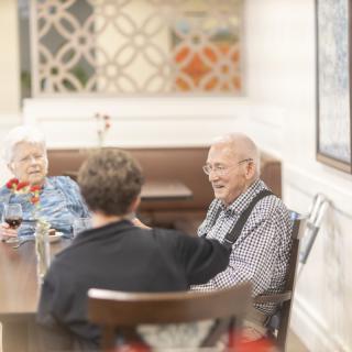 A group of people enjoying a conversation at a dining table indoors.
