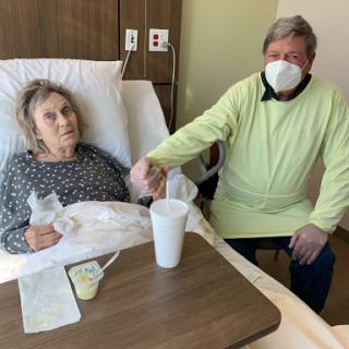 A caregiver provides emotional support to a patient in a hospital room.