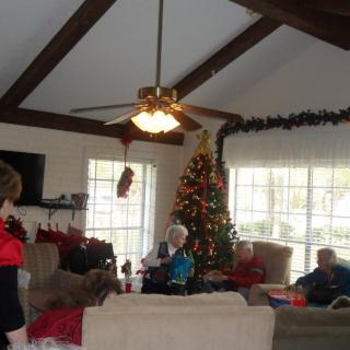 A cozy living room decorated for Christmas with family members gathered around the tree.