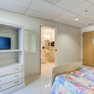 A cozy bedroom with a colorful quilt, featuring a view into an adjoining bathroom.