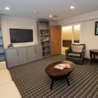 A cozy living room with a television, bookshelf, and comfortable seating.