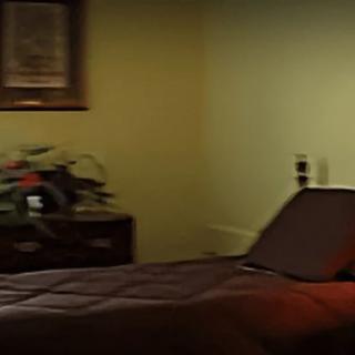 A cozy bedroom with a neatly made bed, a lamp, and decorative elements.
