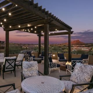 A beautifully lit patio with comfortable seating under a pergola at sunset.