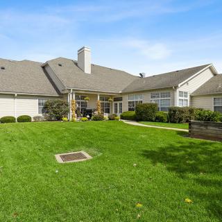 A spacious backyard with a well-maintained lawn and a charming residential house.