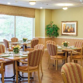 A cozy dining area with multiple tables and chairs, decorated with plants and artwork.