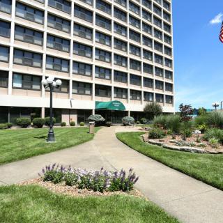 A well-maintained hotel exterior with landscaped gardens and a pathway leading to the entrance.