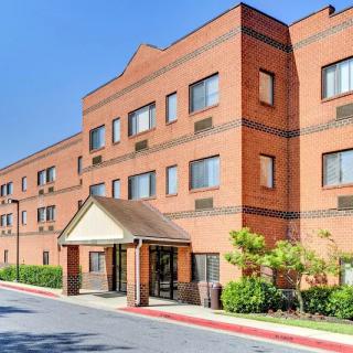 A brick hotel building with an entrance canopy and surrounding greenery.