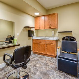 A neatly organized hair salon interior with a styling chair, mirror, and wooden cabinets.