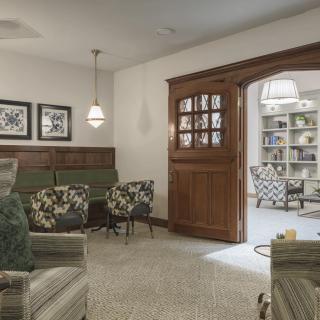 A cozy living room with comfortable seating and a wooden door leading to a room with bookshelves.