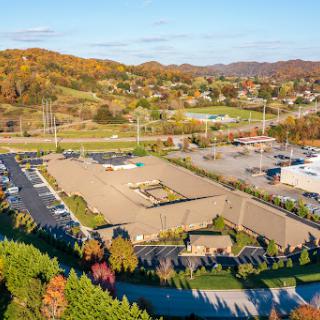 A scenic aerial view of a commercial area showcasing a parking lot and nearby shopping facilities, framed by beautiful autumn colors.