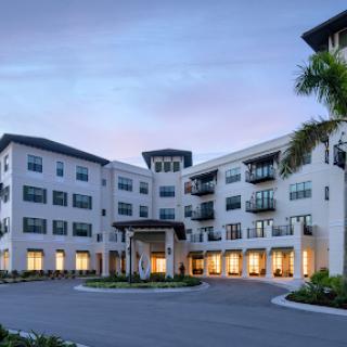 A modern residential building showcasing elegant architecture and well-maintained landscaping during the evening.