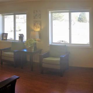 A cozy living room with two chairs next to large windows, featuring wooden flooring and home decor accents.