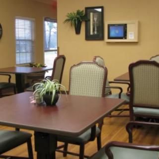 A dining room with tables and chairs, decorated with wall art and plants.