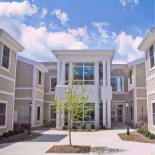 A modern residential building featuring a central courtyard under a bright blue sky.