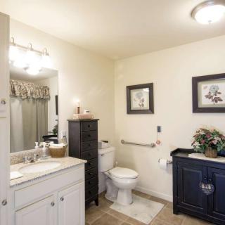 A clean and well-decorated bathroom with a white sink, mirror, and black cabinet.