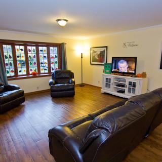 A cozy living room with leather sofas, a television, and large windows.