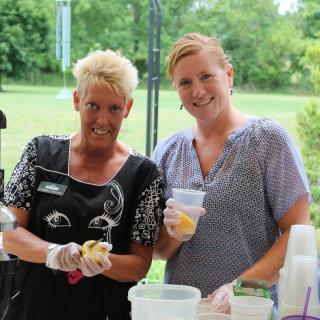 Two women preparing food at an outdoor event.