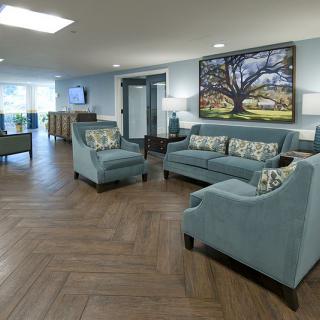 A spacious living room featuring blue furniture and an elegant hardwood floor.