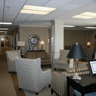 A comfortable lobby seating area with various chairs, lamps, and a decorative mirror on the wall.