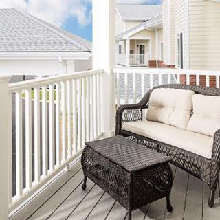 A cozy balcony featuring a wicker sofa with cushions and a matching table, perfect for relaxing outdoors.