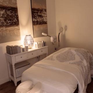 A serene massage room with soft lighting and a cozy treatment table, perfect for relaxation.