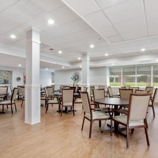 A spacious, well-lit dining area with tables and chairs arranged neatly on a wooden floor.