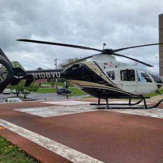 A sleek black and gold helicopter rests on a landing pad, ready for its next flight.