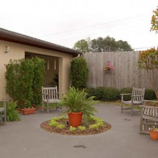 A tranquil outdoor patio area with wooden chairs and a variety of potted plants.