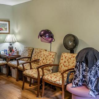 A cozy hair salon waiting area with vintage-style chairs and hair dryers.