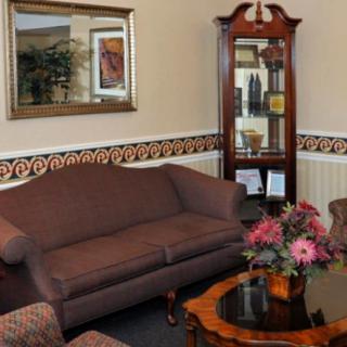 A cozy living room with a brown sofa, coffee table adorned with flowers, and a decorative cabinet against the wall.
