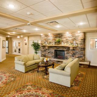 A cozy living room with comfortable sofas and a stone fireplace, featuring warm lighting and elegant decor.