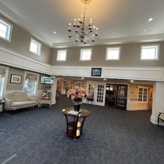 A spacious and elegantly designed lobby featuring a chandelier, seating area, and decorative floral arrangement.