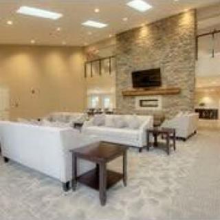 A spacious modern living room with a stone fireplace, a mounted TV, and comfortable white sofas.