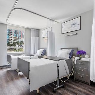 A modern hospital patient room featuring two beds and bright, airy surroundings.