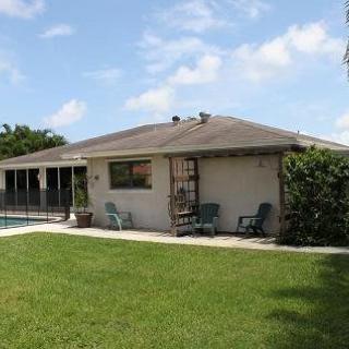 A single-story house with a backyard featuring a lawn and a swimming pool.