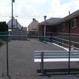 An outdoor fenced area with benches, adjacent to residential buildings.