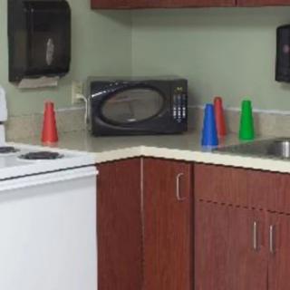 A kitchen corner with a microwave, colorful plastic cones on the countertop, and wooden cabinets.