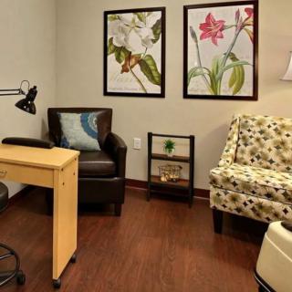 A cozy waiting room with comfortable chairs and floral artwork on the walls.