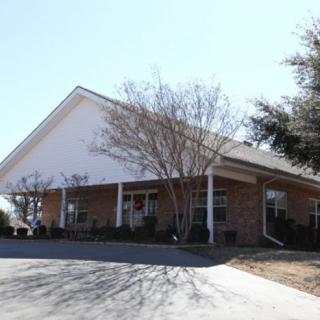 A brick building with a pitched roof surrounded by trees on a clear day.