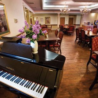 An elegant dining area with a grand piano and floral decor.