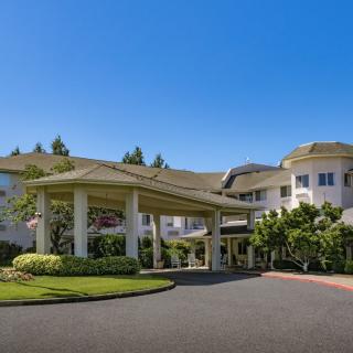 A grand entrance to a large building with a circular driveway and landscaped surroundings.