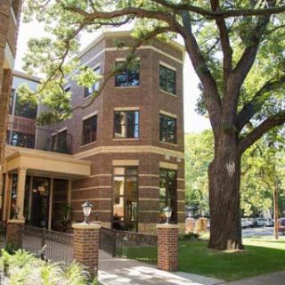 A picturesque brick building surrounded by lush greenery and a large tree.