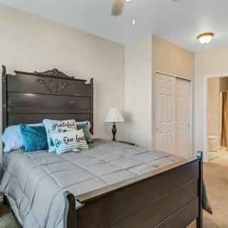 A cozy bedroom with a dark wooden bed, decorative pillows, and a bedside lamp.
