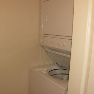 A small laundry area with a stacked washing machine and dryer.