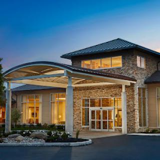 A beautifully designed modern building with an inviting entrance, glowing warmly against the evening sky.