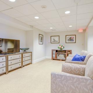 A cozy basement living area with a couch, television, and artwork on the walls.