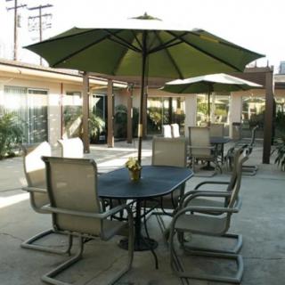 A patio with a table and several chairs under an umbrella.