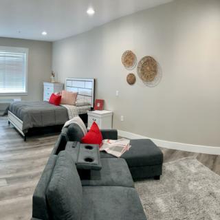 A modern, minimalist bedroom featuring a cozy bed and sofa with red accents.