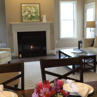 A cozy living room with a fireplace, sofas, and a dining area in view.